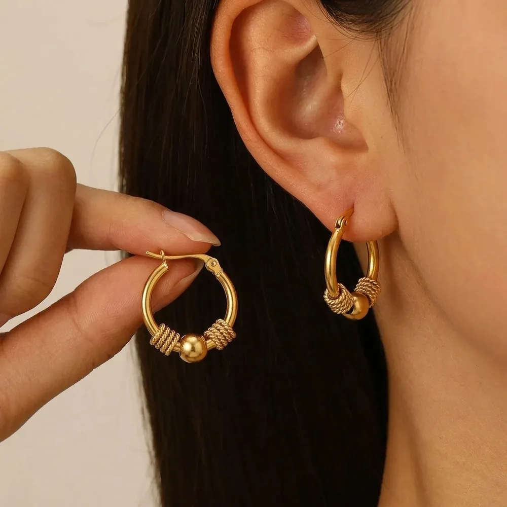 Aro dorado con bolitas de acero inoxidable en la oreja